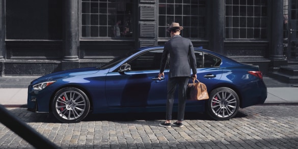 A man opening the front door of 2024 INFINITI Q50 luxury sedan